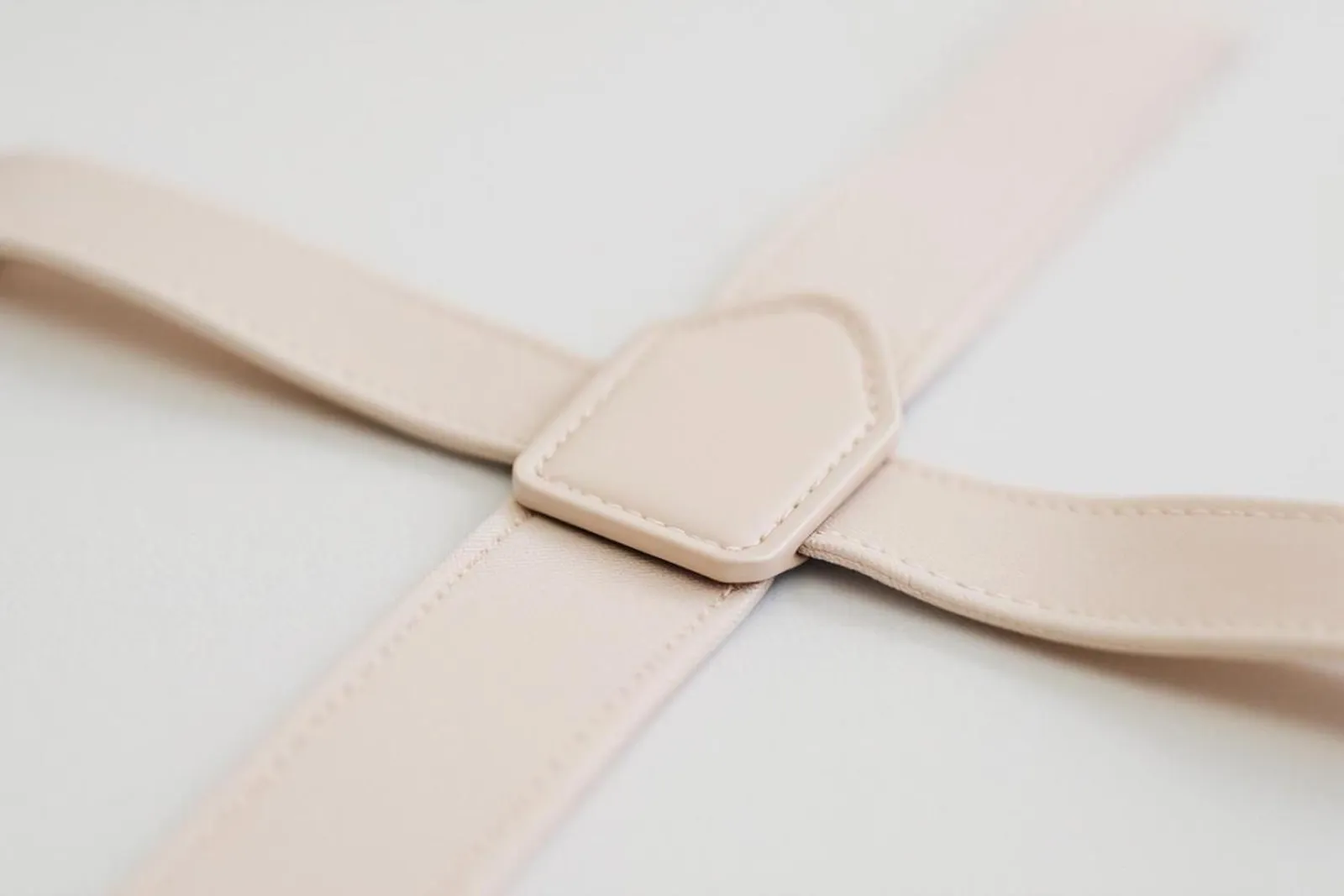 Tenue de mariage masculine avec bretelles beige clair, chemise blanche et costume bleu marine, présentée dans une ambiance élégante et naturelle.