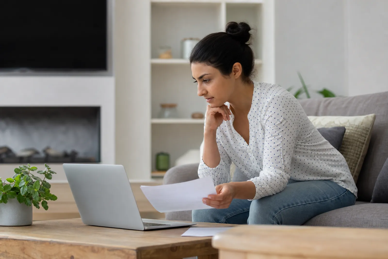 Une personne consulte un relevé bancaire sur un ordinateur portable dans un intérieur calme et lumineux.
