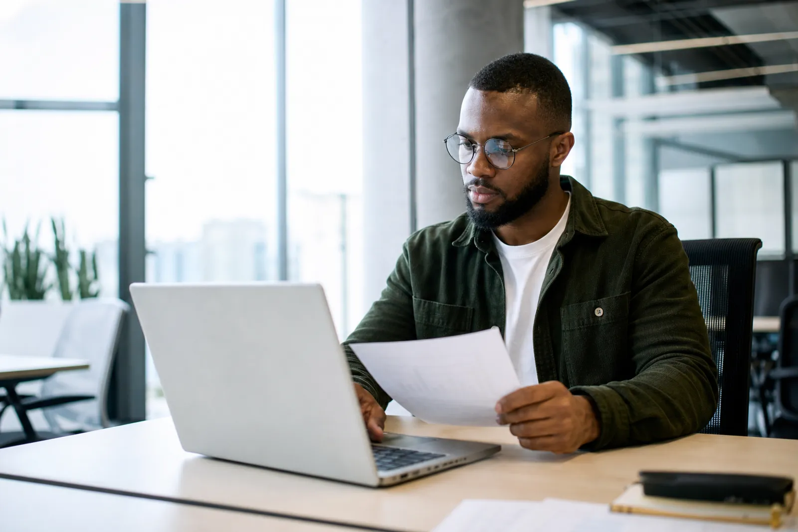 Un salarié consulte un relevé d'épargne salariale sur un ordinateur portable, dans un bureau lumineux.