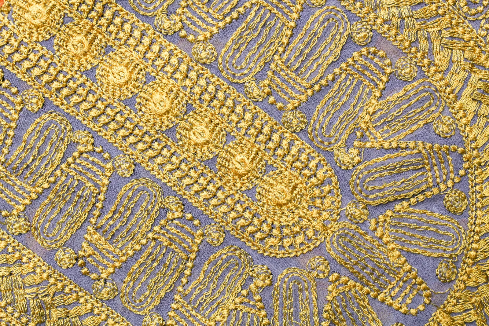 Une artisane kazakhe brodant délicatement un textile cérémoniel au fil doré dans un atelier baigné de lumière naturelle.