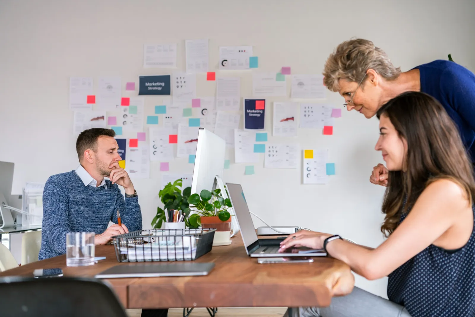 Un professionnel de bureau utilise un ordinateur portable sur lequel s’affiche une interface de productivité, avec des graphiques et un carnet sur le bureau.