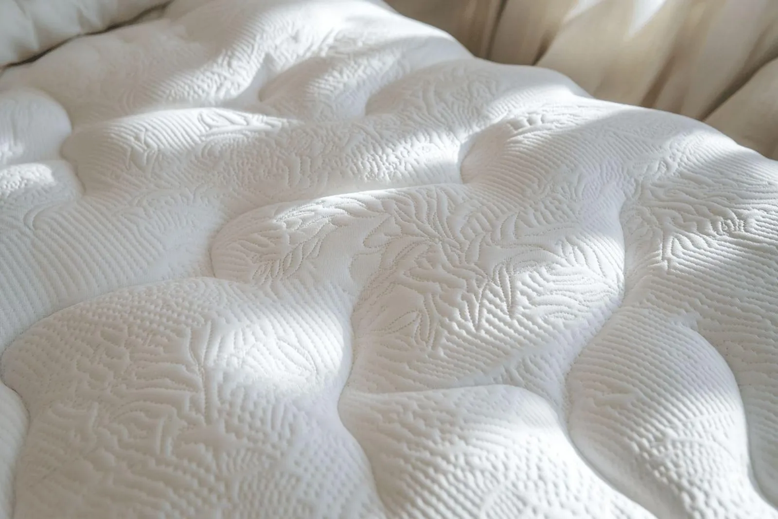 Un protège matelas propre et bien ajusté sur un lit, dans une chambre lumineuse et soignée.