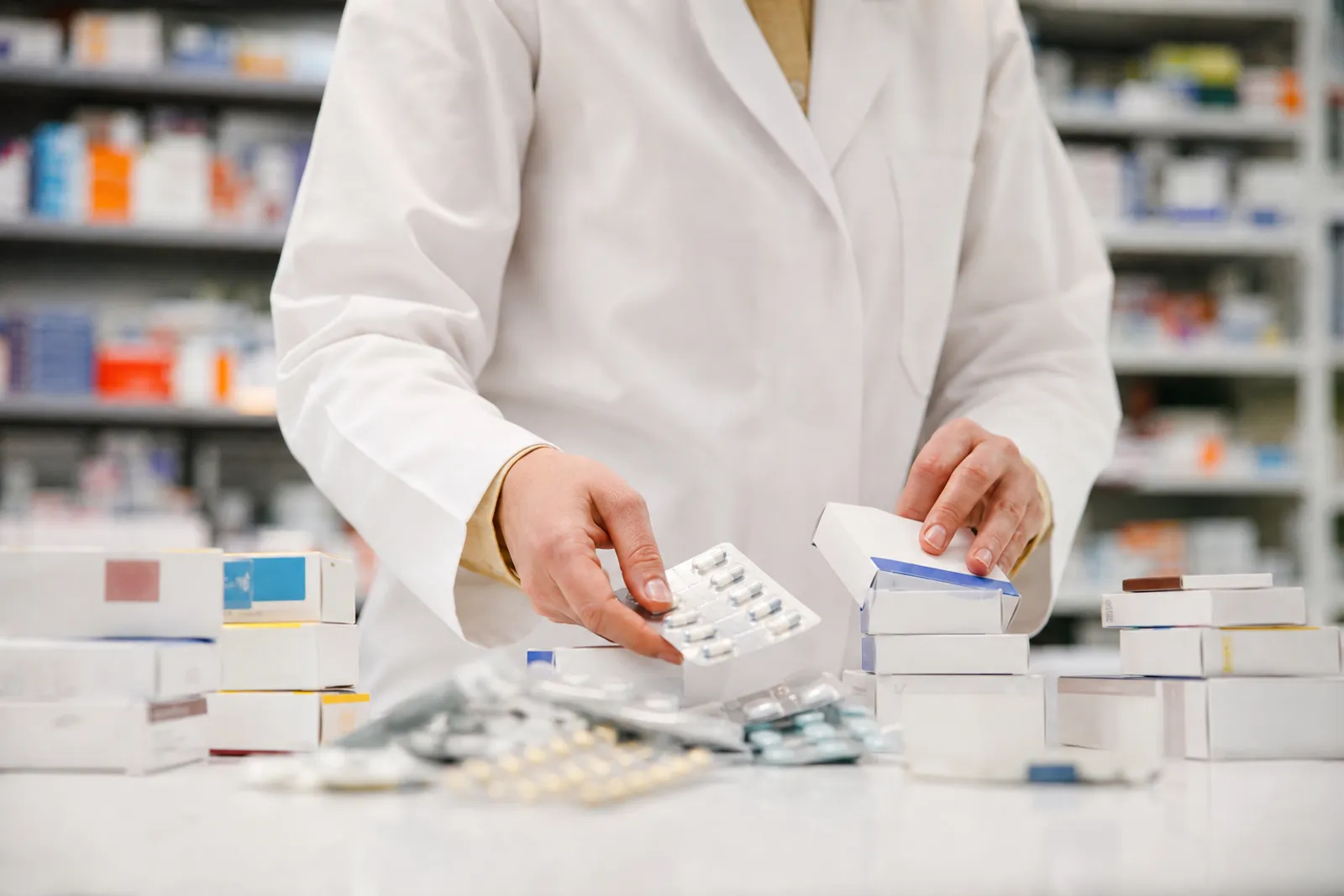Des boîtes de médicaments et un sac de collecte posés sur un comptoir de pharmacie.